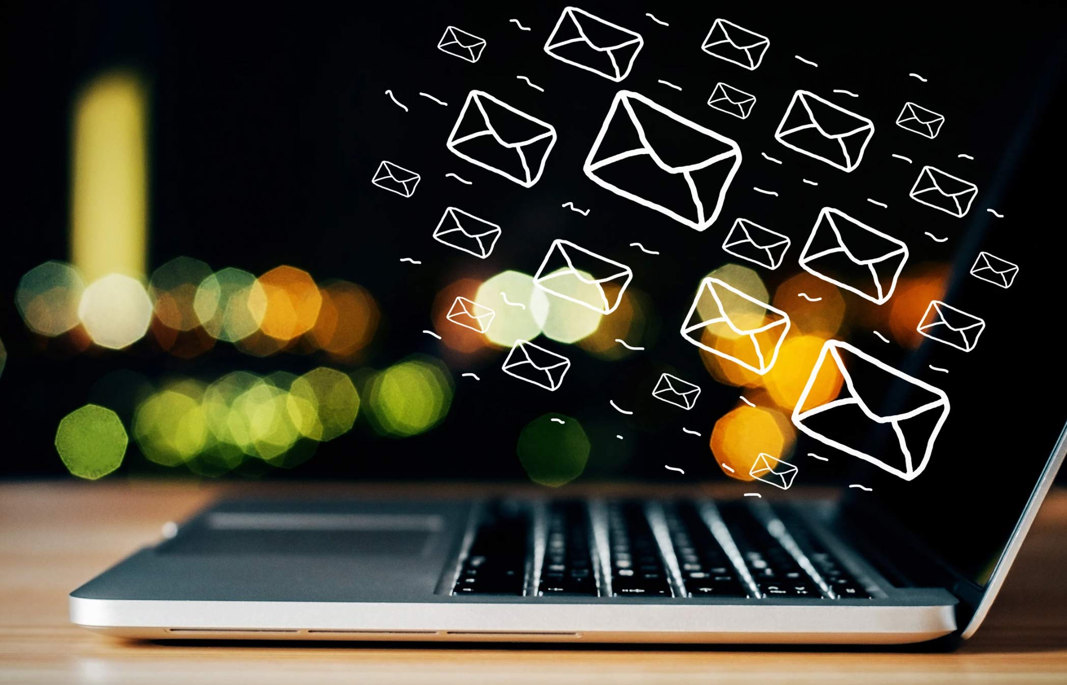 A laptop keyboard with drawn email icons floating above it, symbolizing digital communication.